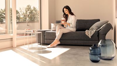 Siemens : une femme se détend sur un canapé en prenant un café