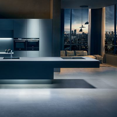 Spacious dark minimalist kitchen with built in appliances and kitchen island at centre