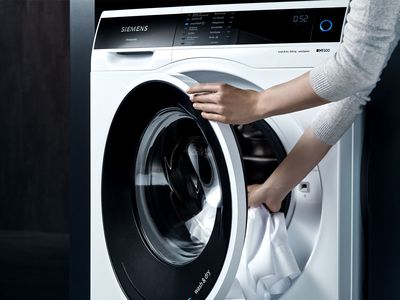 Wäsche wird in neuen iQ500 Waschtrockner gelegt; Link öffnet die Produktseite zum neuen iQ500 Waschtrockner