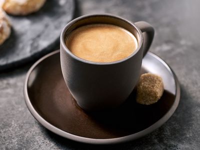 Kopp med espresso och råsockerbit