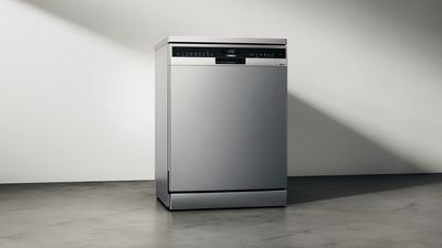 Appareil lave-vaisselle en acier inoxydable contre mur blanc.