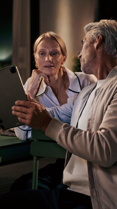 Ein Mann und eine Frau besprechen etwas vor einem Tablet; Link öffnet die Registrierungsseite von My Siemens
