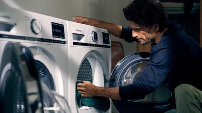 Weiße Siemens Waschmaschine, darauf Maschinenreiniger & ein graues Tuch