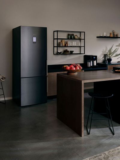 In einer dunkel gestalteten Küche befindet sich ein schwarzer Siemens Kühlschrank in der freistehenden Variante.