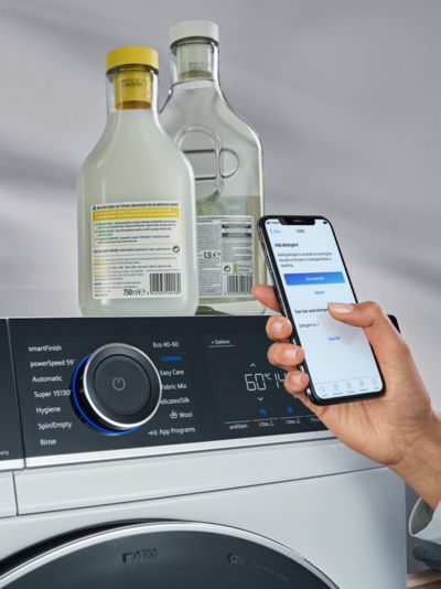 Eine Person nutzt ein Smartphone vor einer iQ700 Waschmaschine.