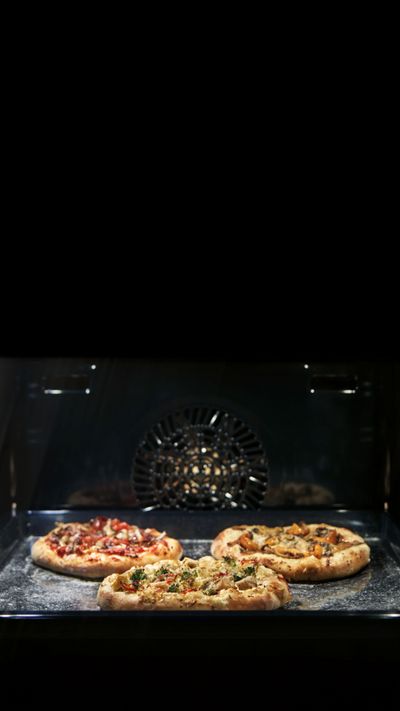 Bild på tre pizzor som gräddas ugn
