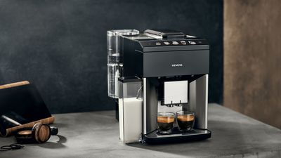 The EQ500 is placed on a kitchen island, with various specialty coffees in glasses and cups in front of it.