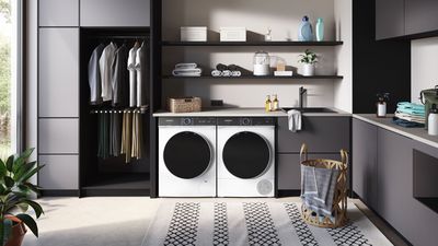 In einem modern gestalteten Zimmer befindet sich ein iQ700 Trockner, der neben einer Siemens iQ700 Waschmaschine steht.