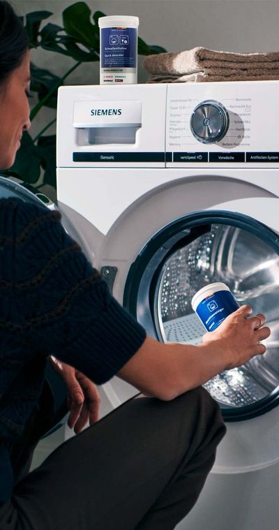 Una donna che usa un detergente per la sua lavatrice Siemens.