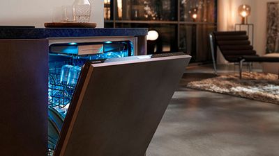 Vaatwasser met gloeiend blauw interieur, open deur onthullen schone gerechten, moderne keuken interieur.