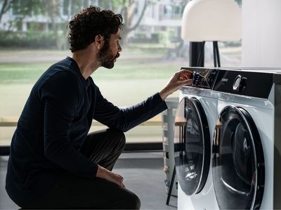 Ein Mann startet im knien eine Waschmaschine von Siemens