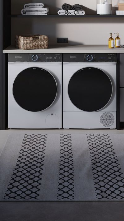 Eine Siemens Waschmaschine in einem Waschraum mit Pflanzen und Wäscheständer.