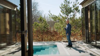 Richard Juhlin holder en kop kaffe og står foran en udendørs pool