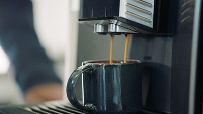 Friskbrygget kaffe fra espressomaskine flyder ind i espressokop