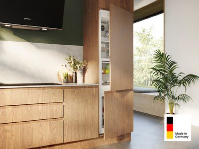Ein Siemens Einbau Gefrier-und Kühlschrank Made in Germany in einer modernen Küchenzeile aus Holz. Die Türen des Geräts sind geöffnet und gefüllt mit Lebensmitteln.