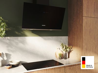 Eine Siemens Made in Germany Dunstabzugshaube über einem Kochfeld eingebaut in einer modernen Küchenzeile aus Holz.