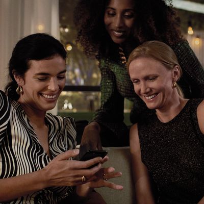 A group of girlfriends checking out the screen of a smartphone