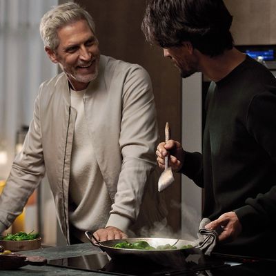 Two men conversing while cooking at an induction hob