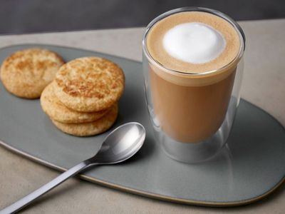 Flat White Kaffee in einem Glas auf einer Platte mit Keksen