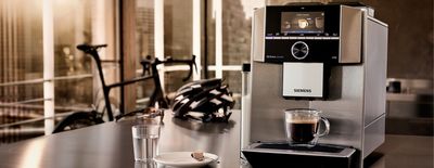 Siemens EQ.9 Kaffeevollautomat steht auf einem Tisch, ein Fahrrad befinden sich im Hintergrund
