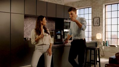 Ein junges Paar steht in der Küche und freut sich über die Vorteile eines leisen Siemens Kaffeevollautomaten.