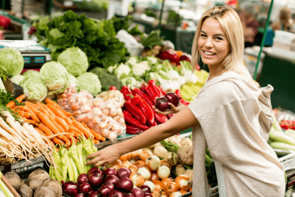 Žena kupuje zeleninu na místním trhu s potravinami. 
