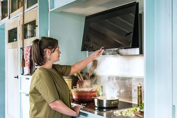 A woman using an extractor hood with the Home Connect function