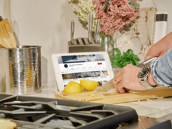 ipad displaying chef guided videos on countertop while a person is cooking