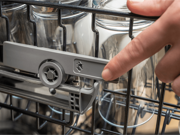 Hand pointing to specific part of inside a dishwasher