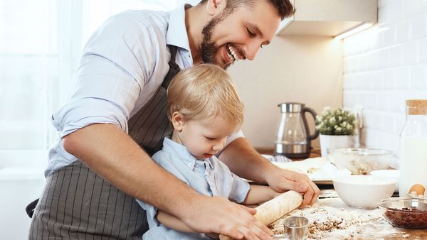 En ung mann lager mat sammen med en liten gutt 
