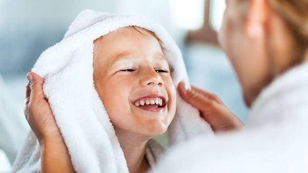 The photo shows a happy, smiling boy being dried off with a towel.