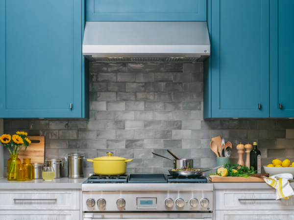 Wall hood with blue cabinetry and thermador range