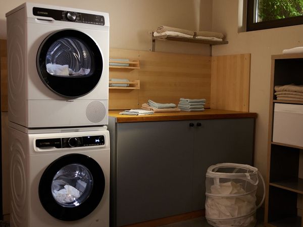 Ένα μπάνιο με δύο συσκευές η μια πάνω στην άλλη, στεγνωτήριο και πλυντήριο.