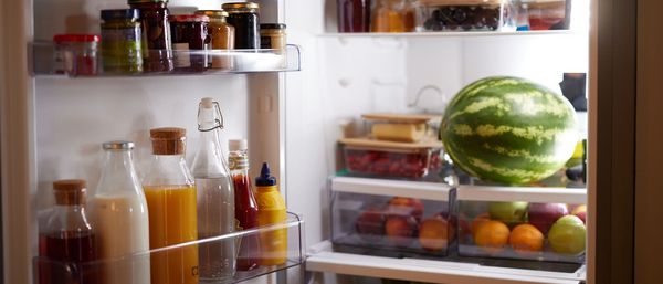 Ένα ανοιχτό ψυγείο γεμάτο φρούτα, λαχανικά, τρόφημα, χυμούς και σάλτσες-μαρμελάδες.