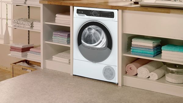 Ένα στεγνωτήριο μέσα σε μια κατασκευή ντουλαπιών όπου δεξιά και αριστερά του στα ντουλάπια, έχει σιδερωμένα διπλωμένα ρούχα.