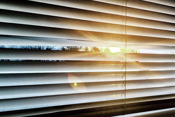Sonnenreflektion im Fenster mit heruntergelassener Jalousie