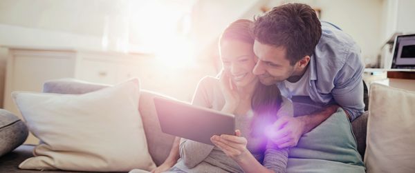 Ein junges Pärchen bedient voller Freude die Home Connect App