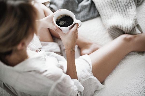 Frau entspannt mit einer Tasse Kaffee auf dem Sofa