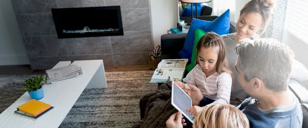 Familie sitzt auf dem Sofa mit einem Tablet und bedient die Home Connect App