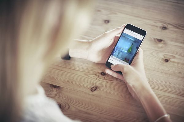 Frau prüft den Kühlschrankinhalt mit der Home Connect App