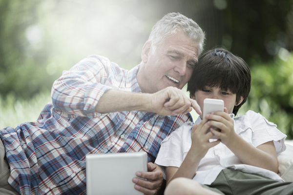 Mann zeigt seinem Sohn auf dem Smartphone die Home Connect App