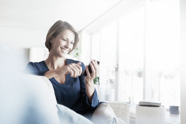 A young woman engaging the child lock for her Home Connect oven from her sofa