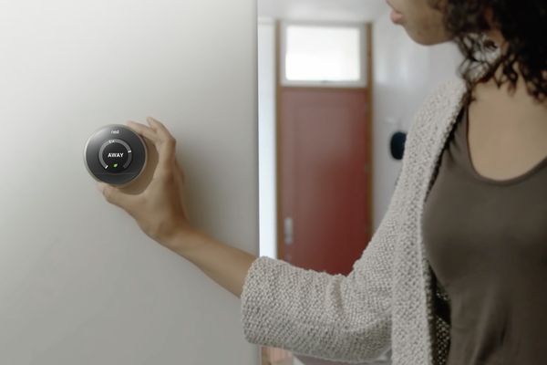 Nainen muuttaa asetuksia Nest-termostaatilla, joka on yhdistetty Home Connect -sovellukseen
