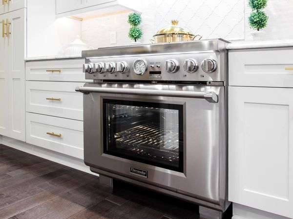 Thermador 36 inch range side shot with oven light on and gold accents in kitchen