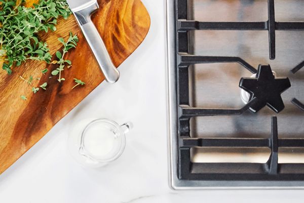 Thermador gas cooktop next to cutting board and herbs 