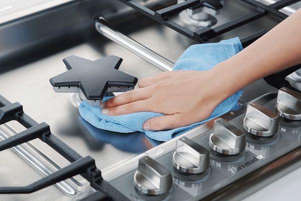 Woman cleaning gas cooktop star burner 