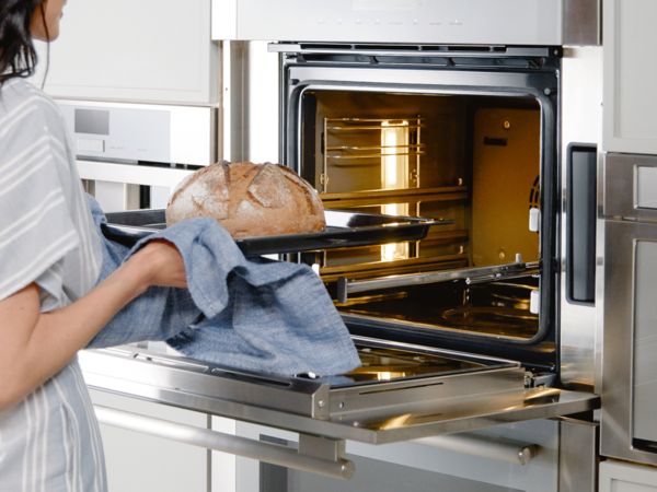 Thermador Masterpiece Collection Steam Oven with woman taking bread out