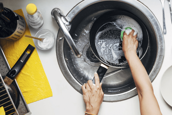 La imagen muestra la limpieza de platos con detergentes naturales