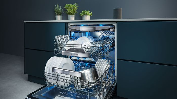 Open built in dishwasher showing items inside surrounded by blue lights