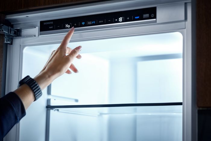 Mano che tocca il display di un frigorifero